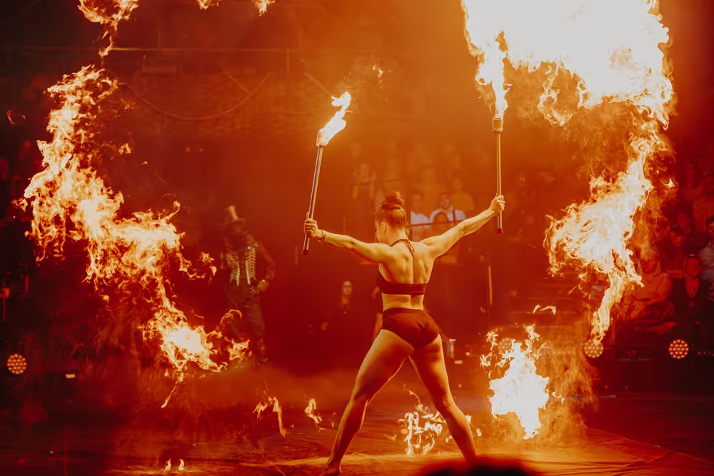 A fire performer with flaming torches in COME ALIVE!