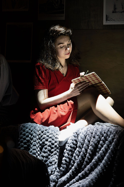 Chloe-Jean Vincent as Anne Frank, writing in her diary by lamplight